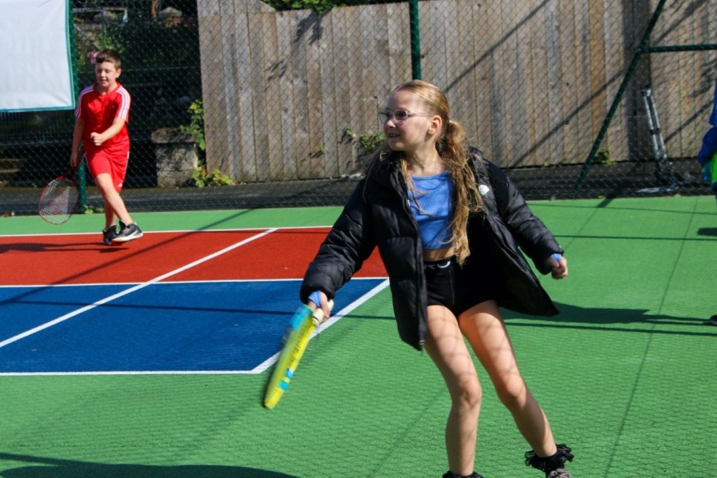 Child playing tennis on outdoor tennis court