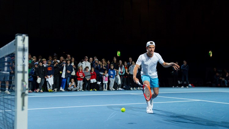 Tennis player Diego Schwartzman practises while a large group of children watches on from the side of the court