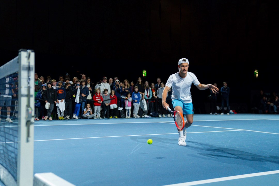 Tennis player Diego Schwartzman practises while a large group of children watches on from the side of the court