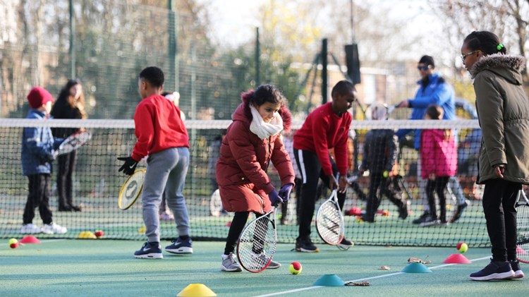 Children playing tennis outside 