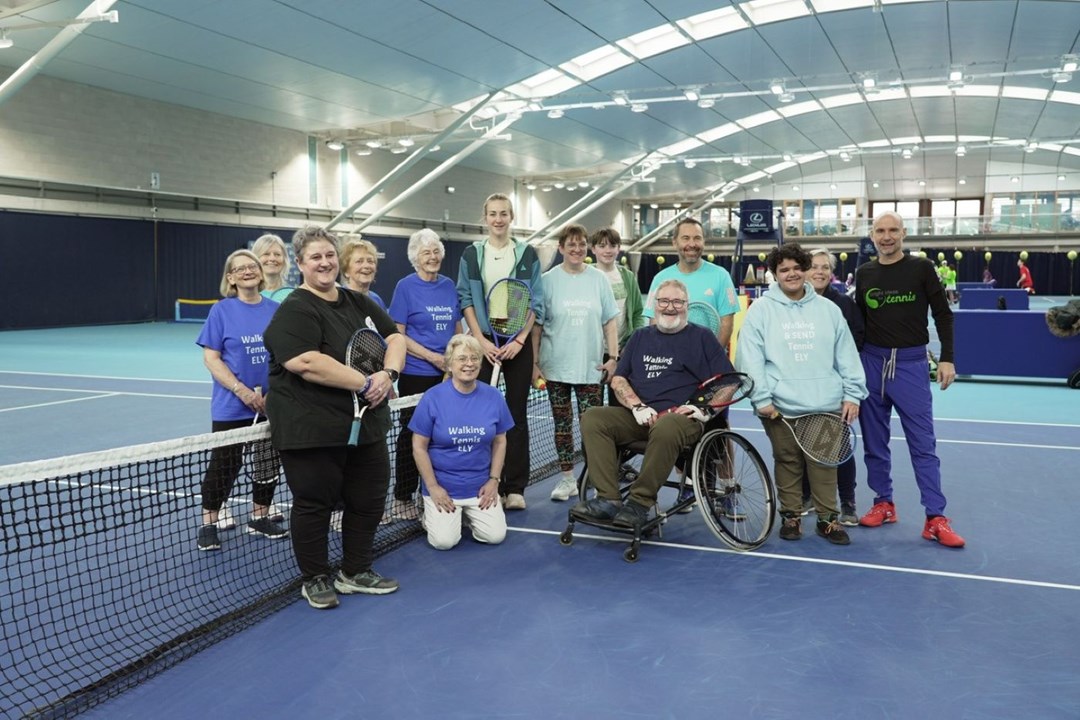 A group of people, one in a wheelchair on court at the National Tennis Centre 