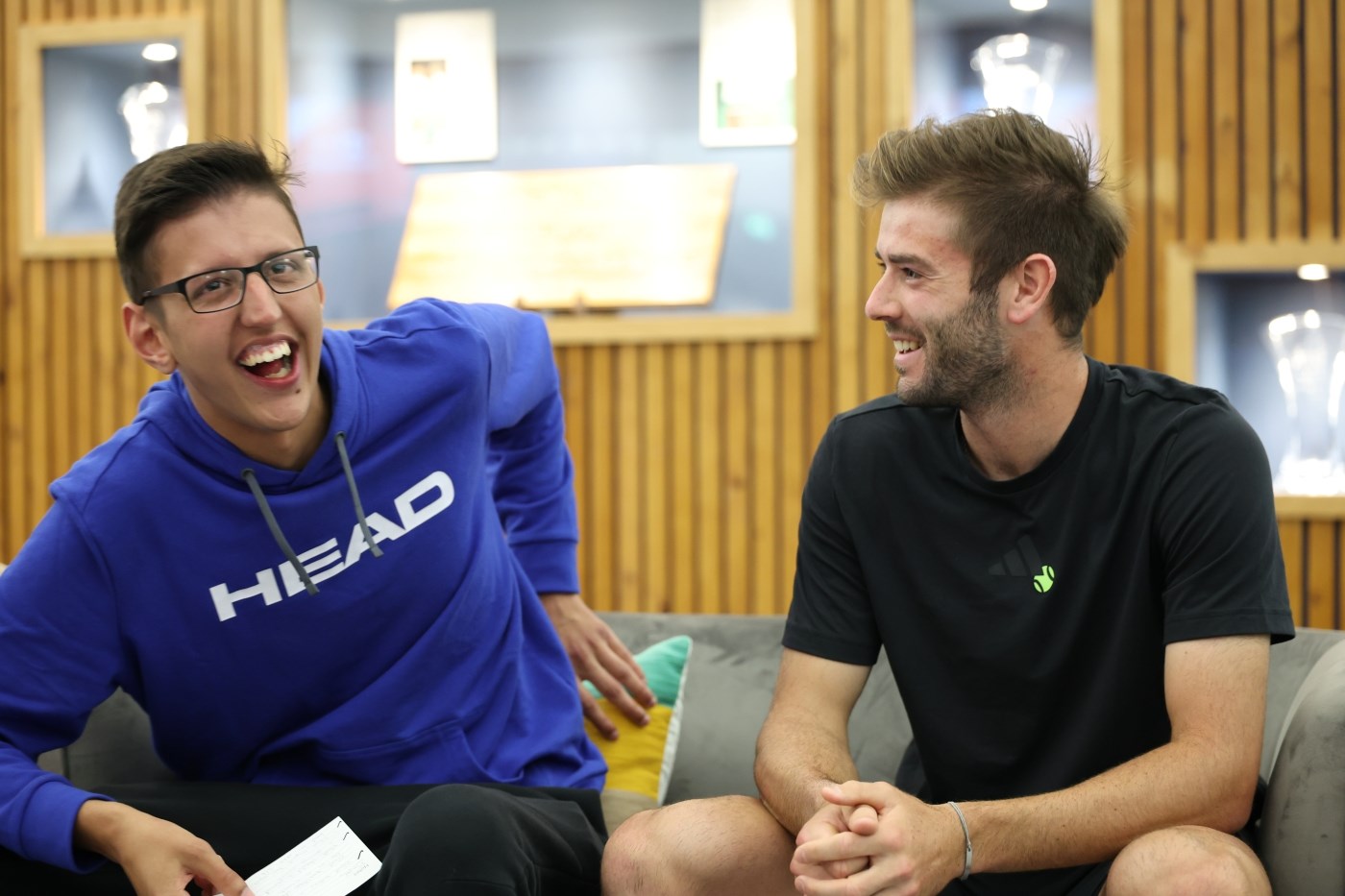 Young man in blue jumper smiling sitting next to Jacob Fearnley