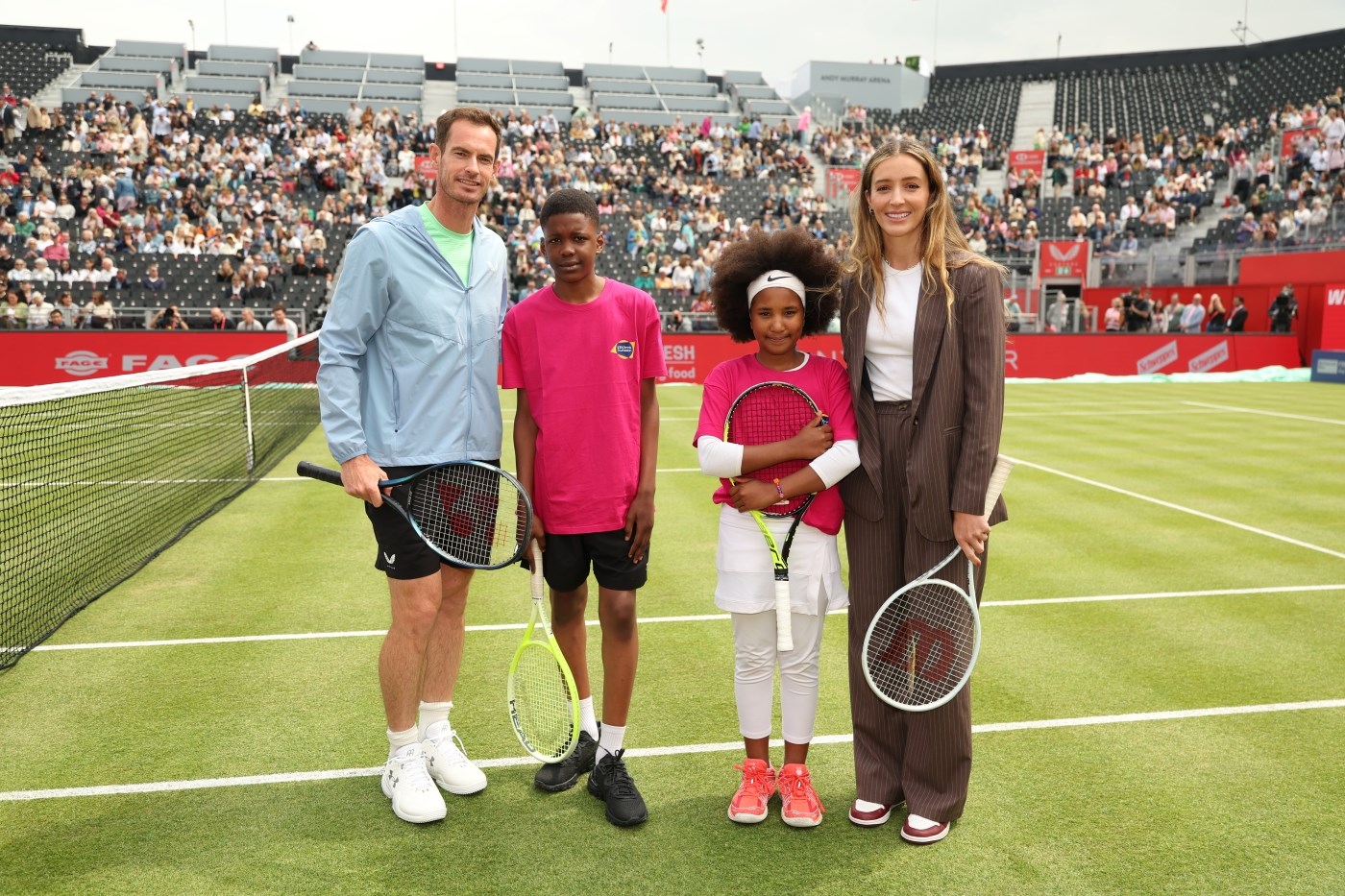 Andy Murray and Laura Robson standing next to young tennis players wearing pink LTA Tennis Foundation t-shirts on court at The Queen's Club