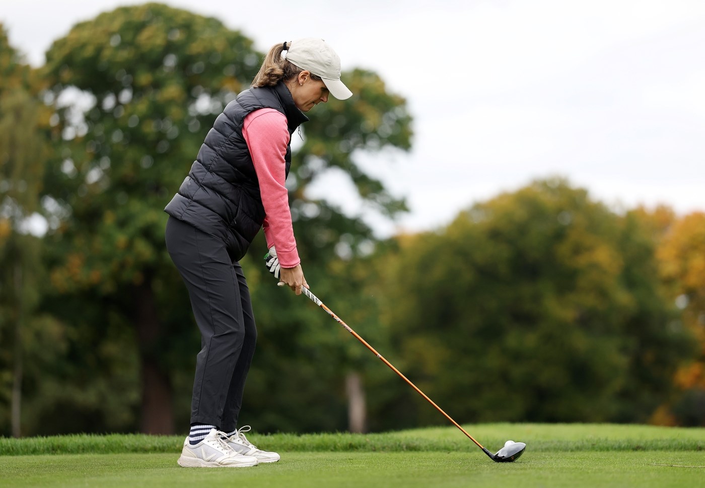 A woman holding a golf club, about to tee off