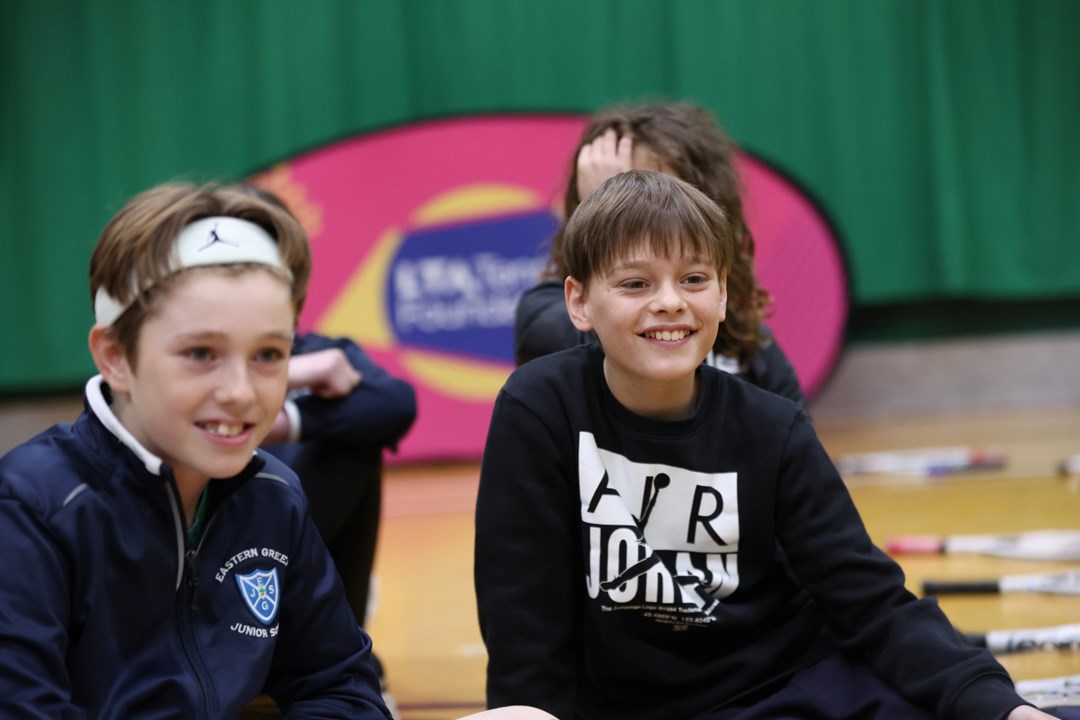 Two boys sitting down and smiling