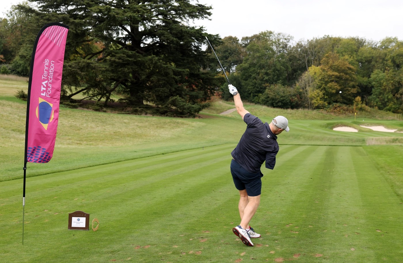 A man photographed from the back, holding his golf club in the air, just after teeing off