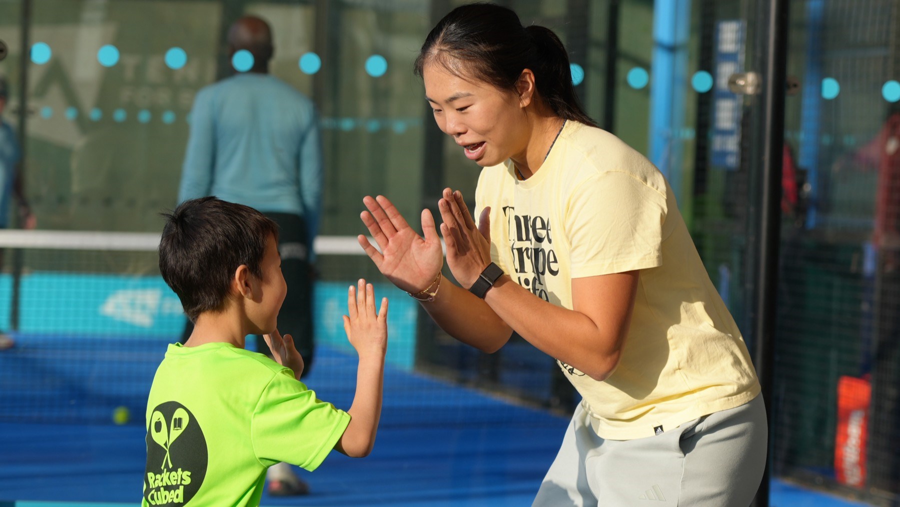 British tennis player Mimi Xu high fiving a young boy on court