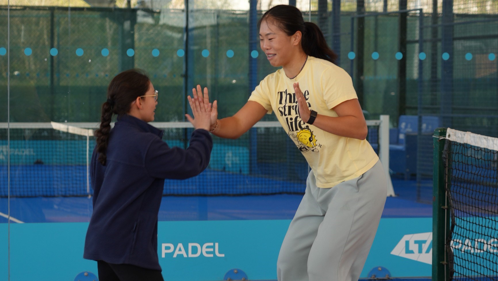 British tennis player Mimi Xu clapping hands with a young girl on court