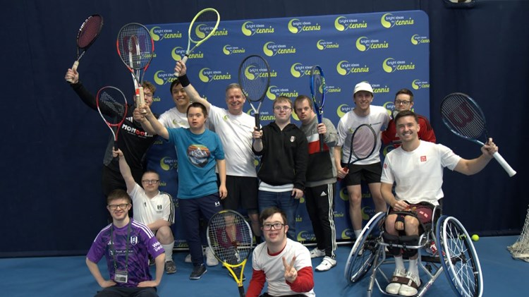 A group of Bright Ideas for Tennis participants with Gordon Reid, holding their rackets in the air