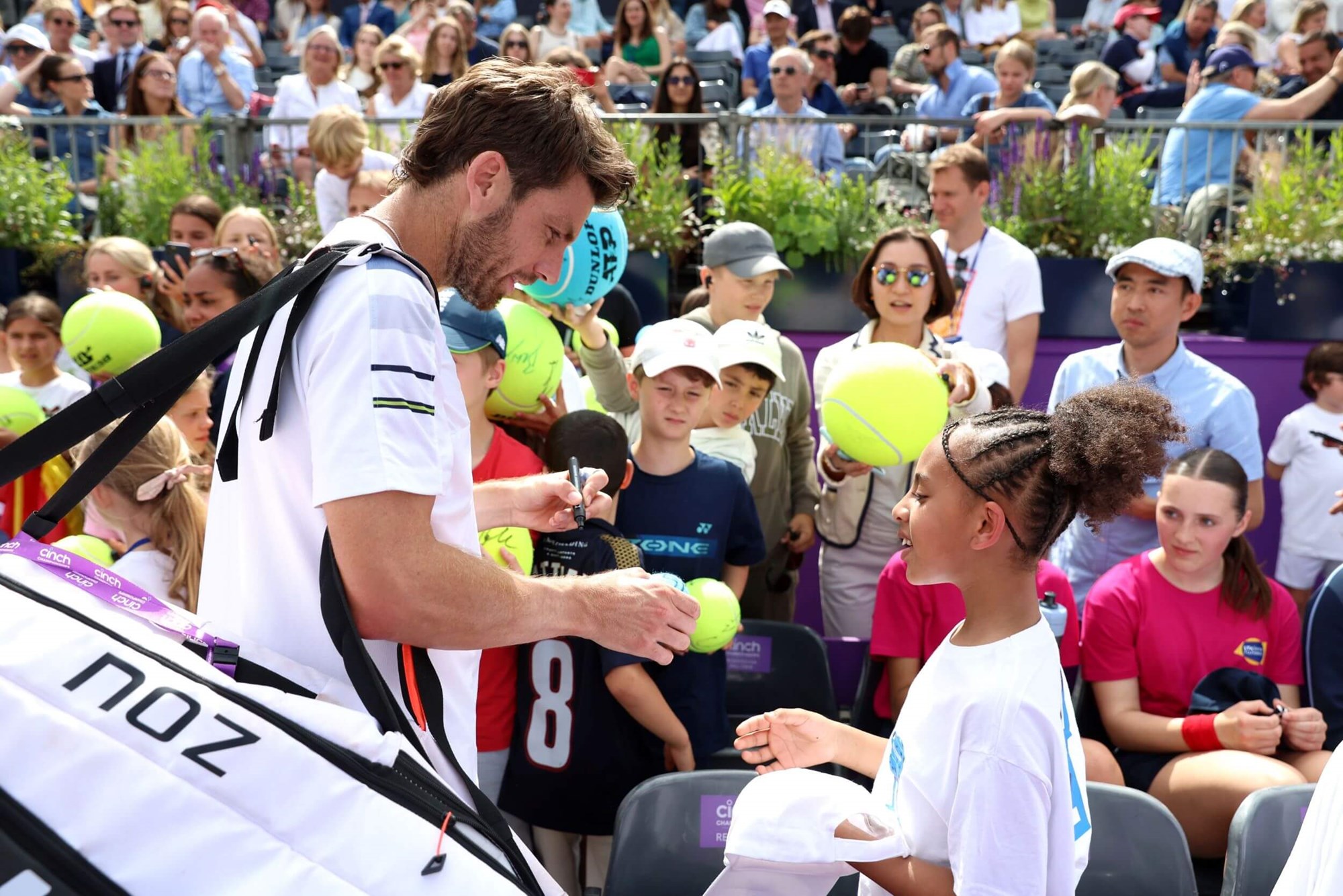 A young fan getting a tennis ball autographed by Cam Norrie as he leaves the court
