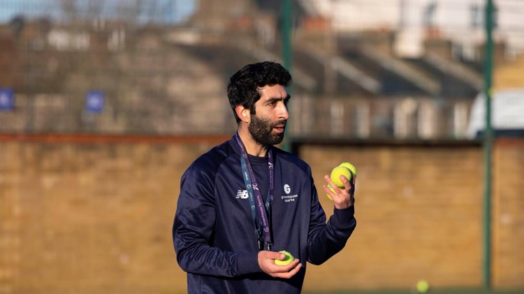 Greenhouse Sports Coach-Mentor holding tennis balls in hand on tennis court 