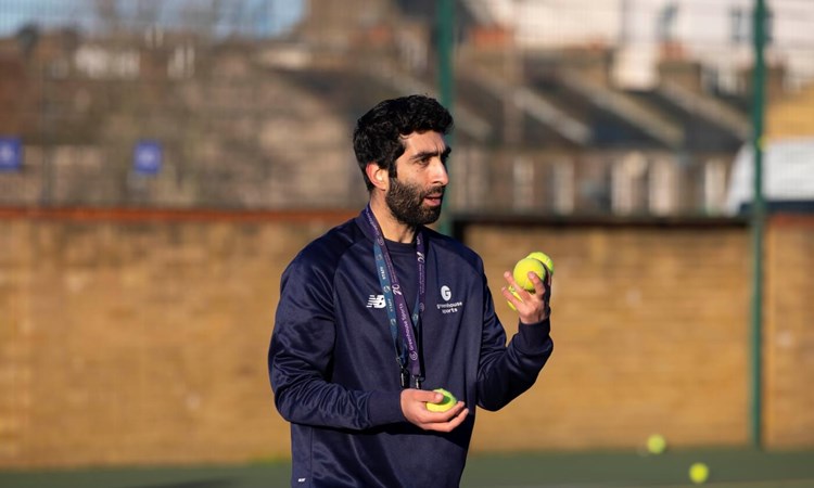 Greenhouse Sports Coach-Mentor holding tennis balls in hand on tennis court 
