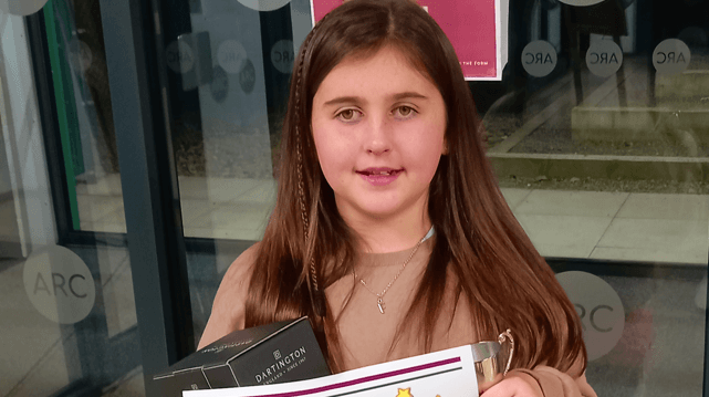 Freya smiling while holding up an ARC Awards certificate