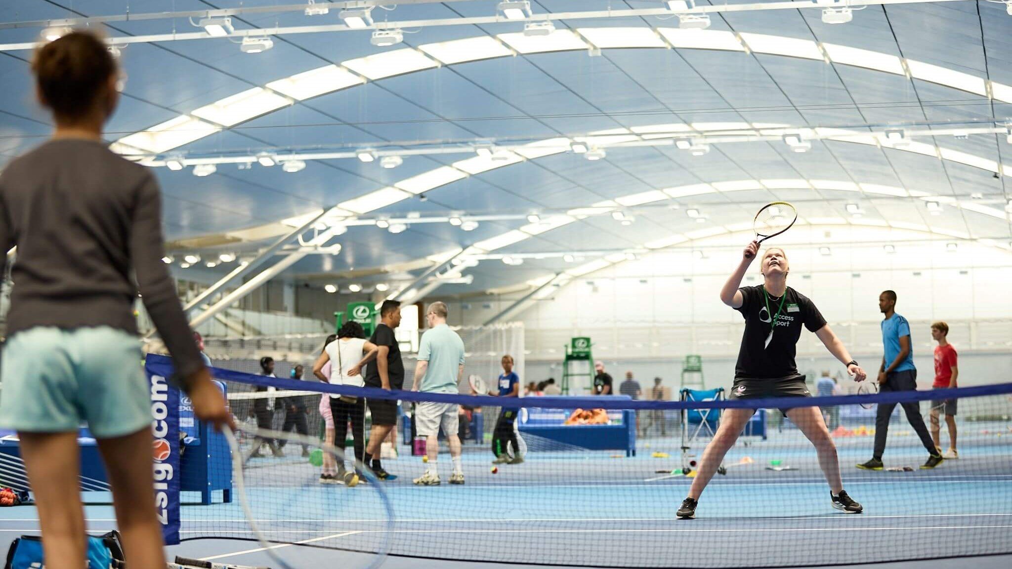 A volunteer vollleys a ball back to a participant