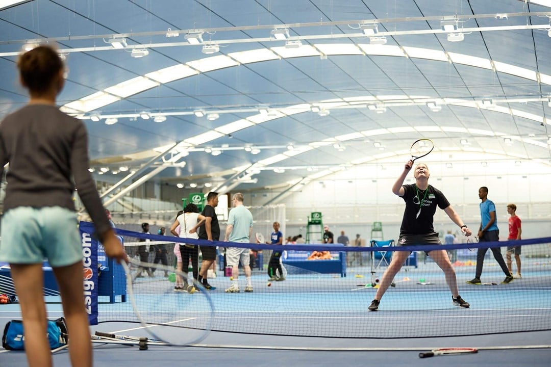 A volunteer vollleys a ball back to a participant