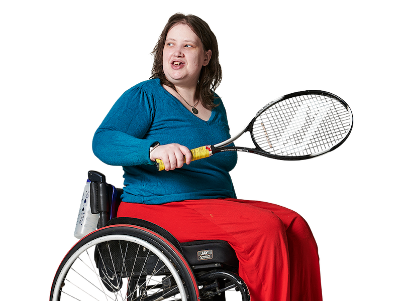 Woman in a wheelchair, with a tennis racket in her hand, looking over her shoulder