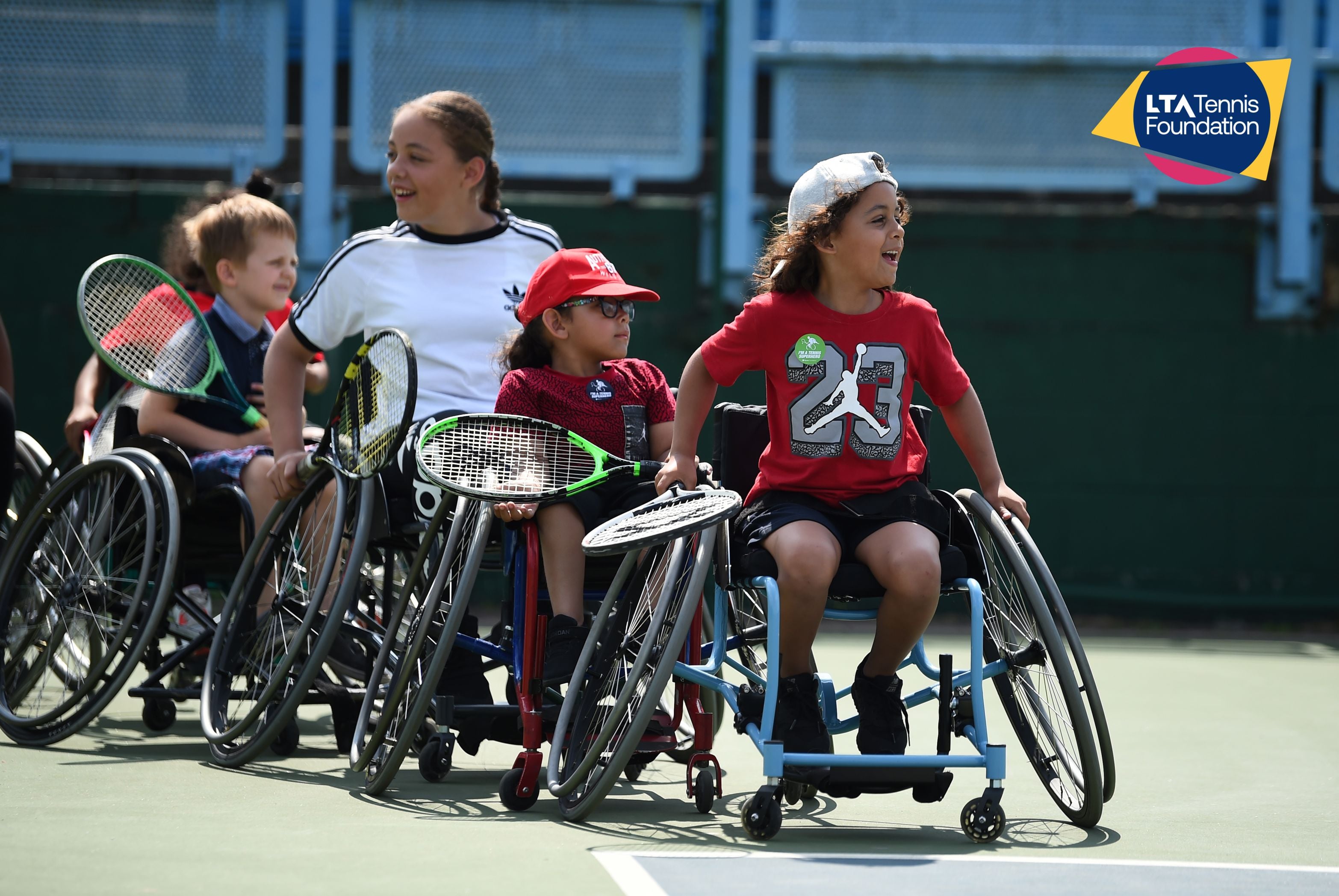 A group of children playing wheelchair tennis