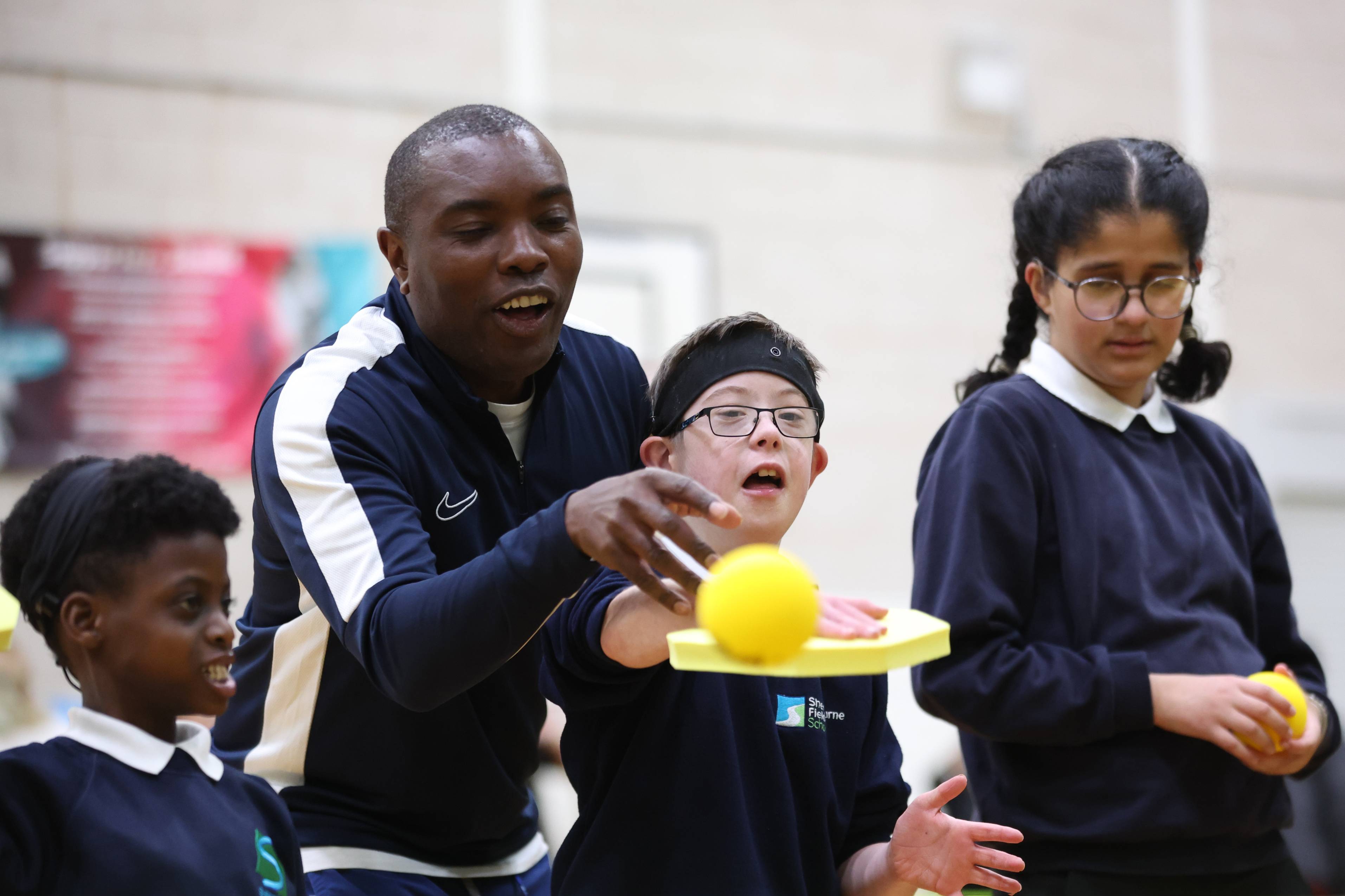 A group of people watch a yellow sponge ball being thrown