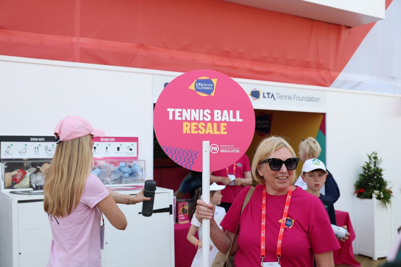 A female volunteer holding a tennis ball resale sign