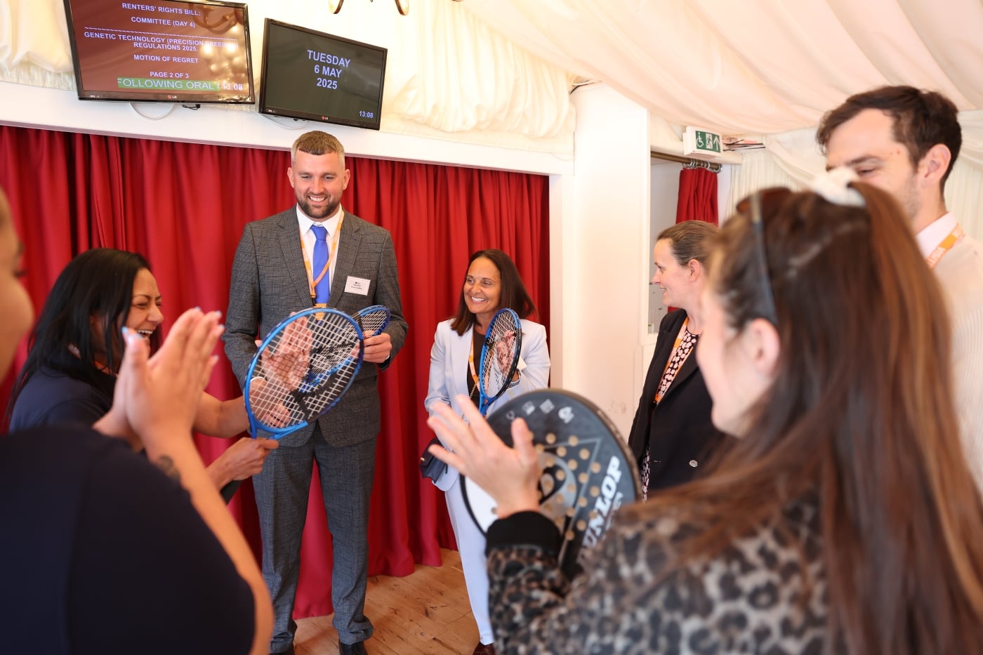 Attendees holding tennis rackets and chatting