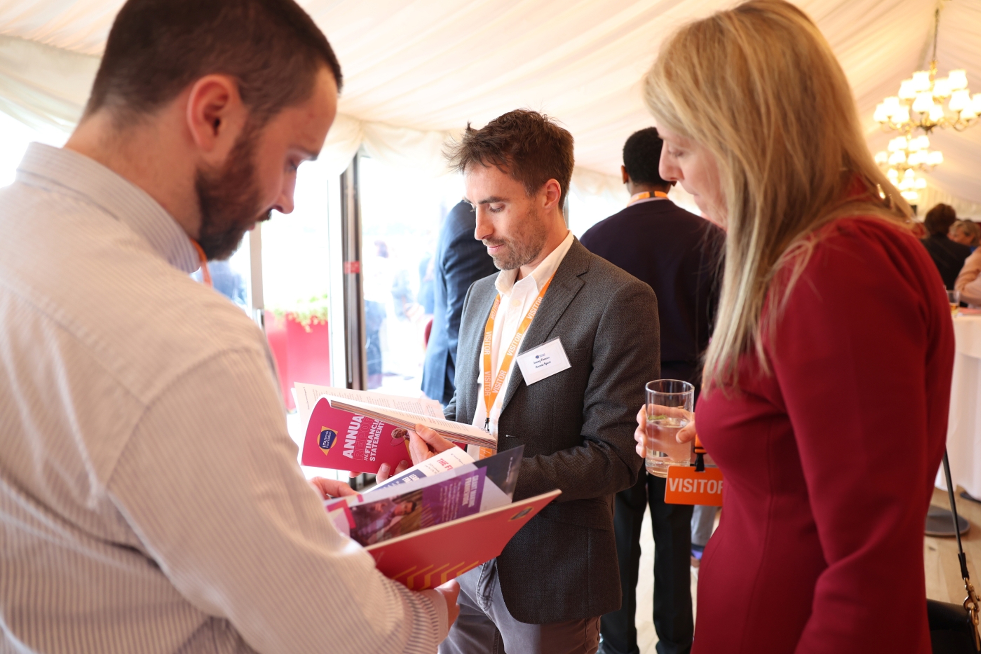 Reception attendees review the annual report brochure