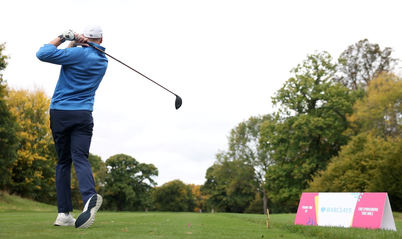 A man photographed from the back, just after teeing off