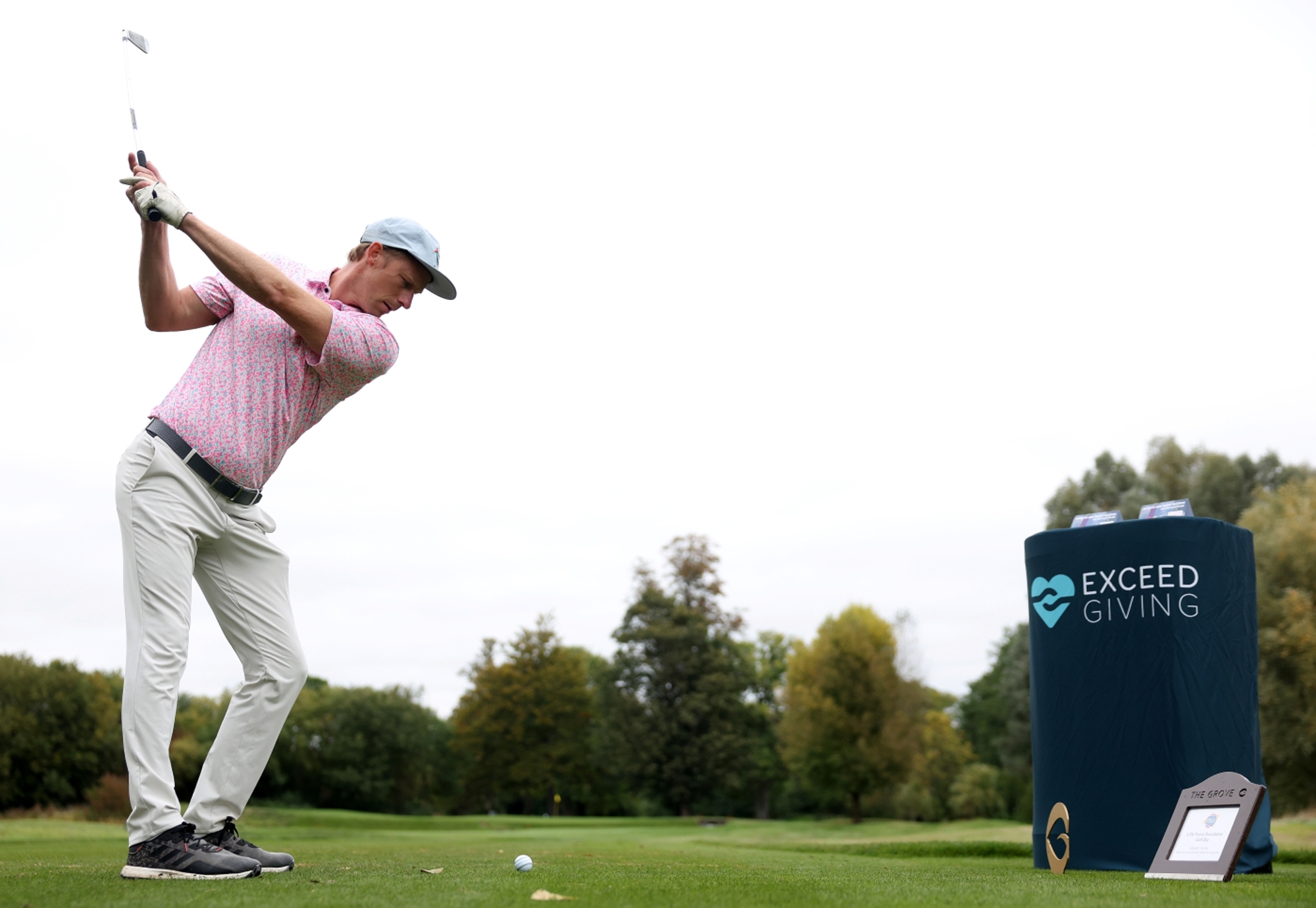 A man holding a golf club up, about to tee off