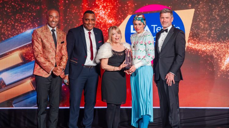 Fi8ve people on stage at sporting equals awards. Two females wining the award with presenters. 