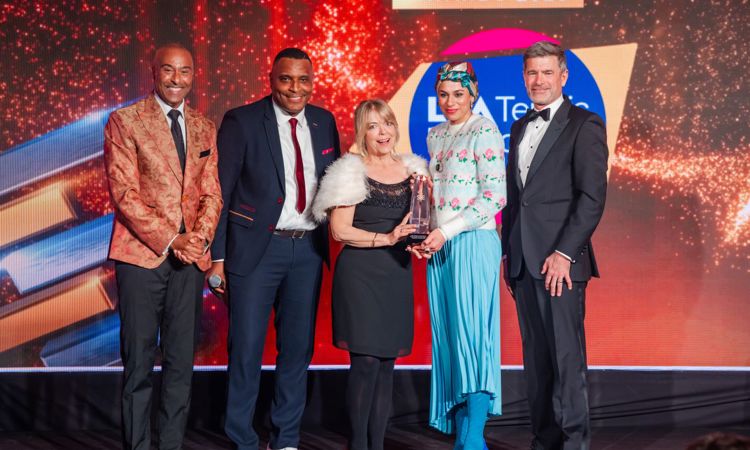 Fi8ve people on stage at sporting equals awards. Two females wining the award with presenters. 