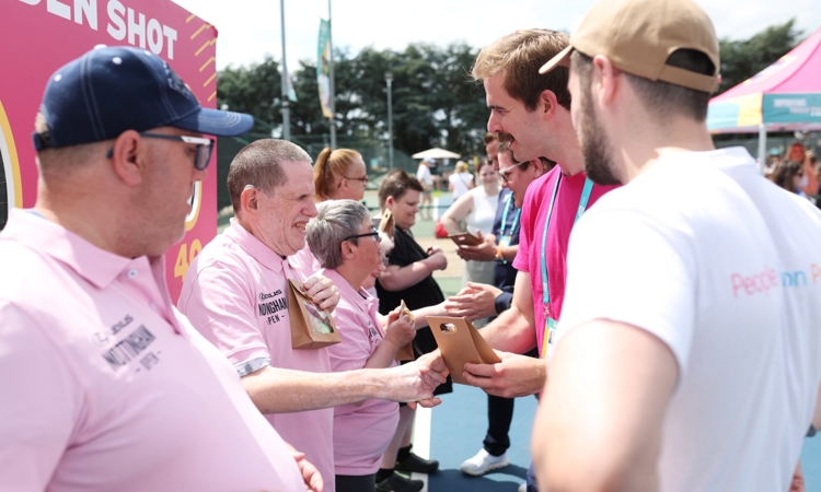 Two lines of people looking at each other shaking hands and presenting a small gift