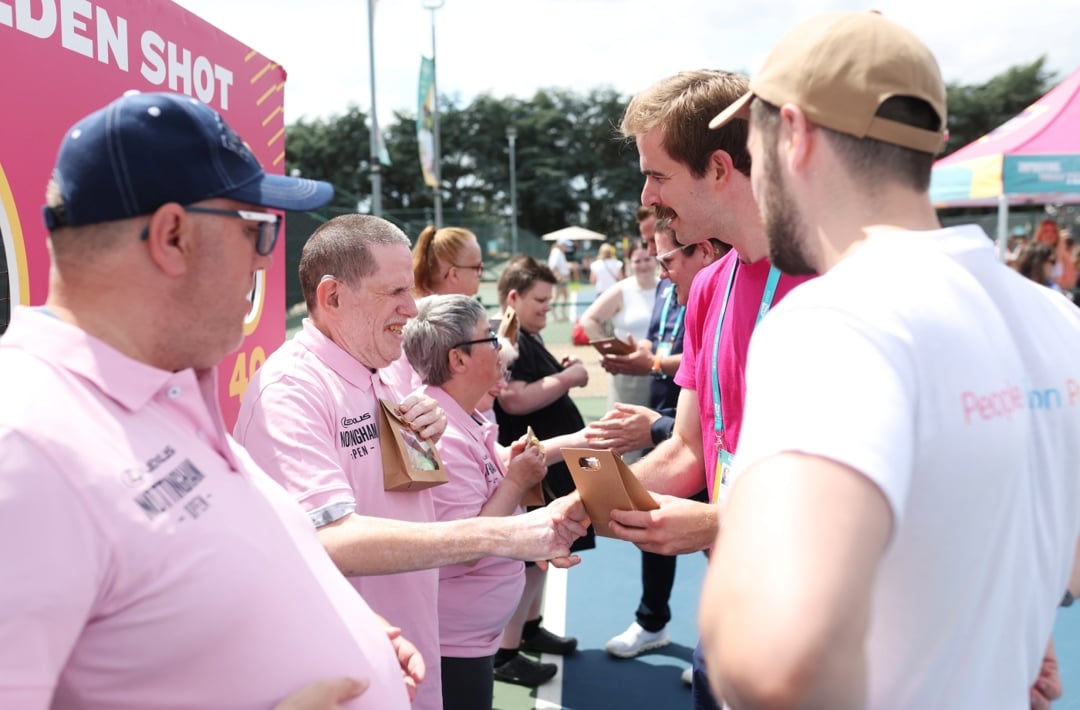 Two lines of people looking at each other shaking hands and presenting a small gift