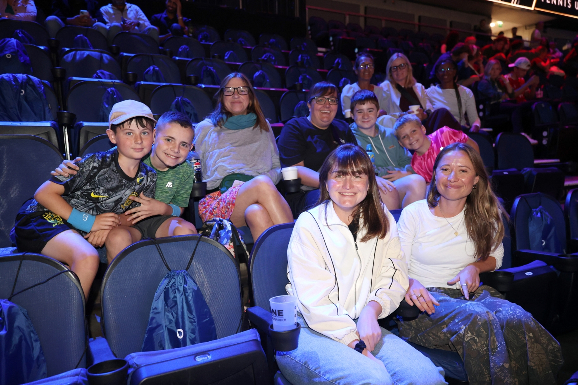 A group of children and young people sitting in rows smiling at the camera 