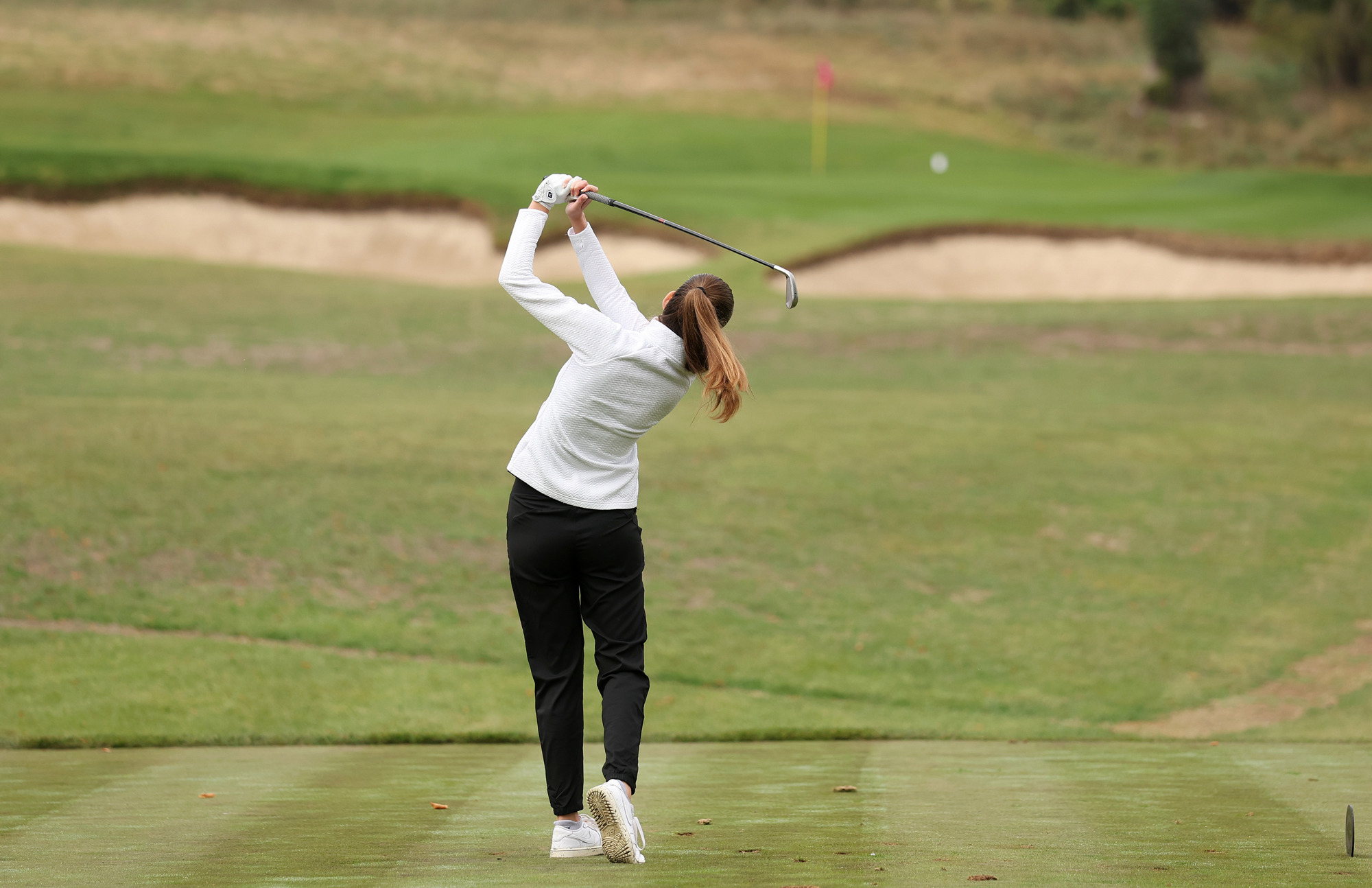 A golfer strikes a ball off the tee