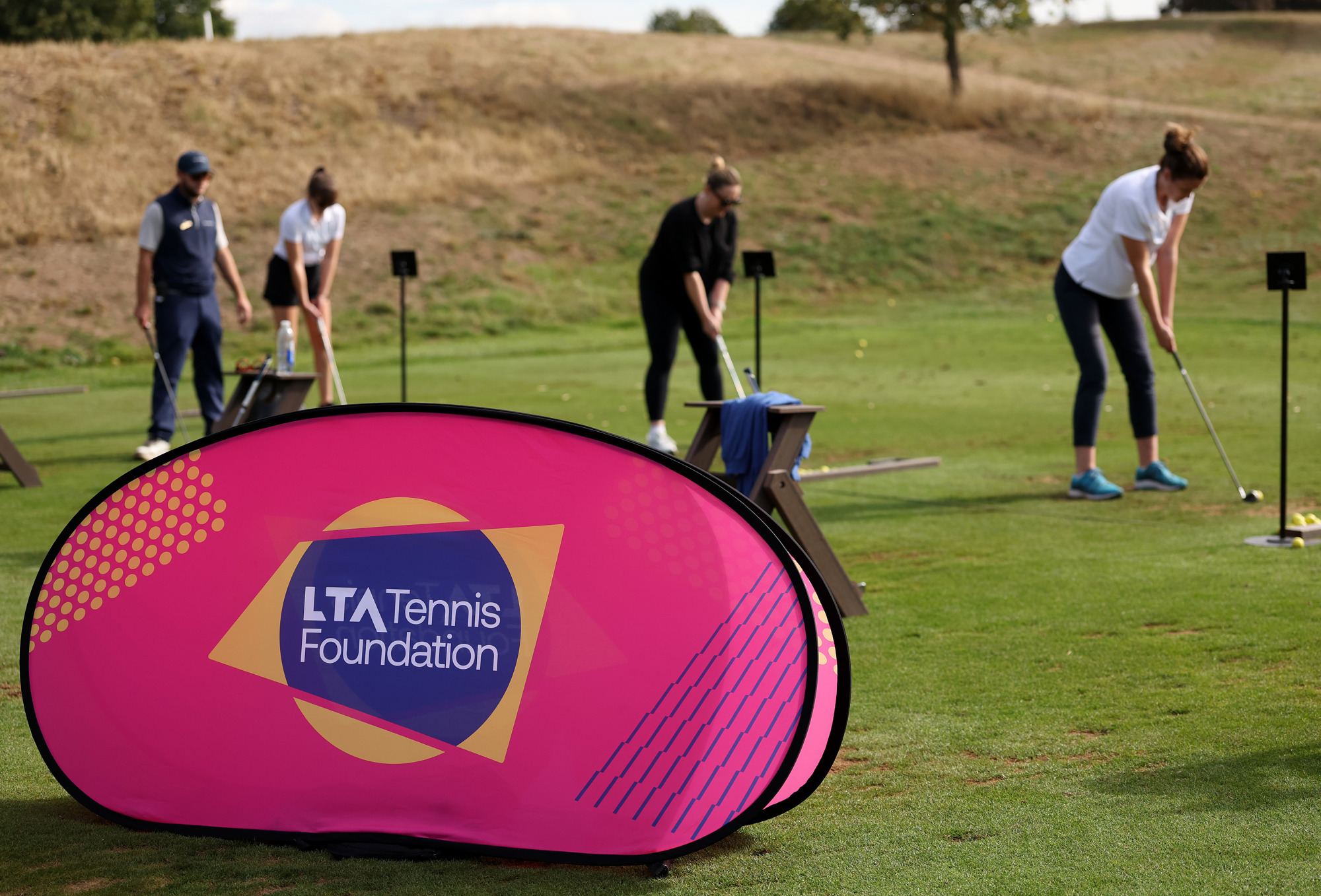 Golfers practice swinging at the driving range
