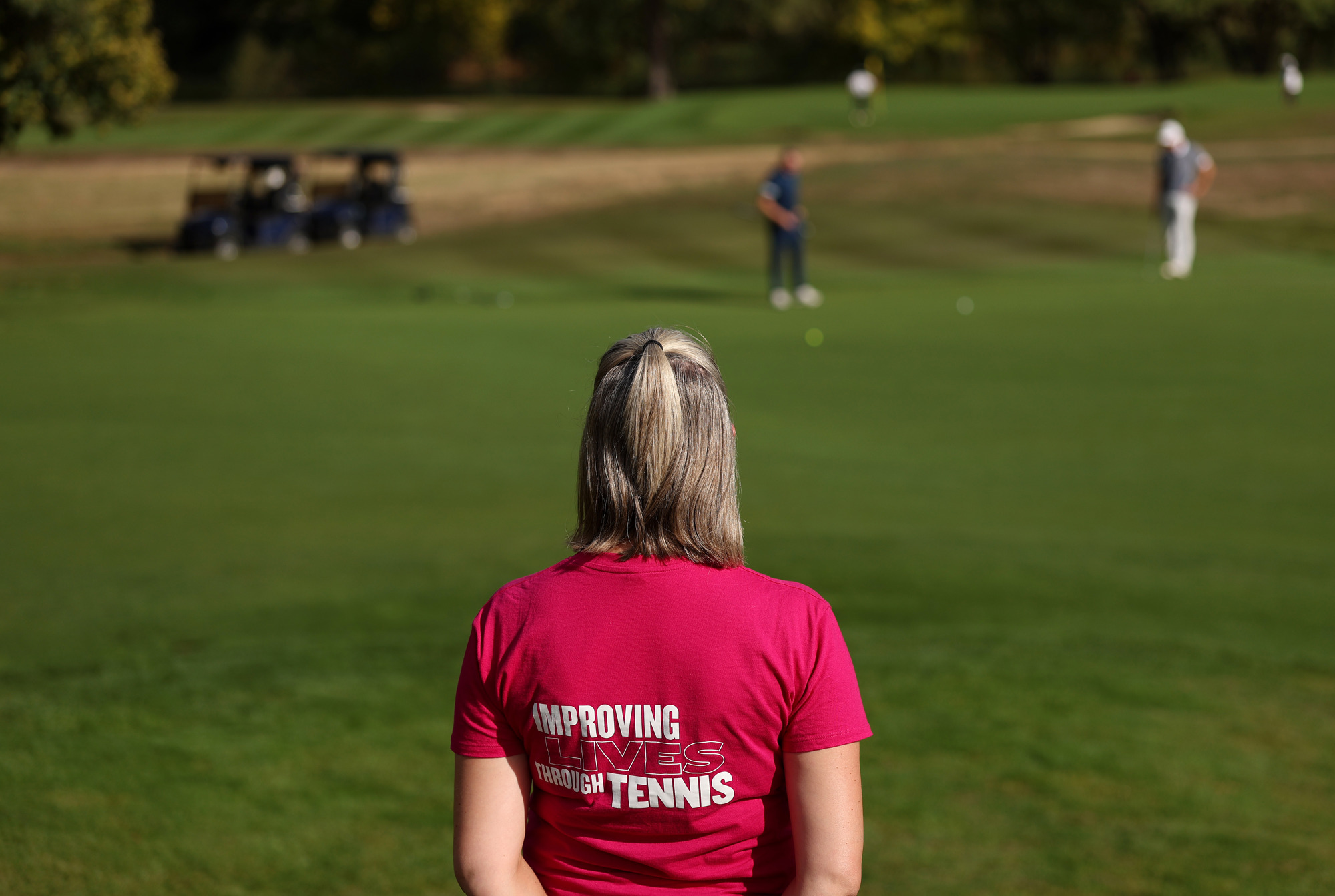 A volunteer in the foreground while golfers put on a green