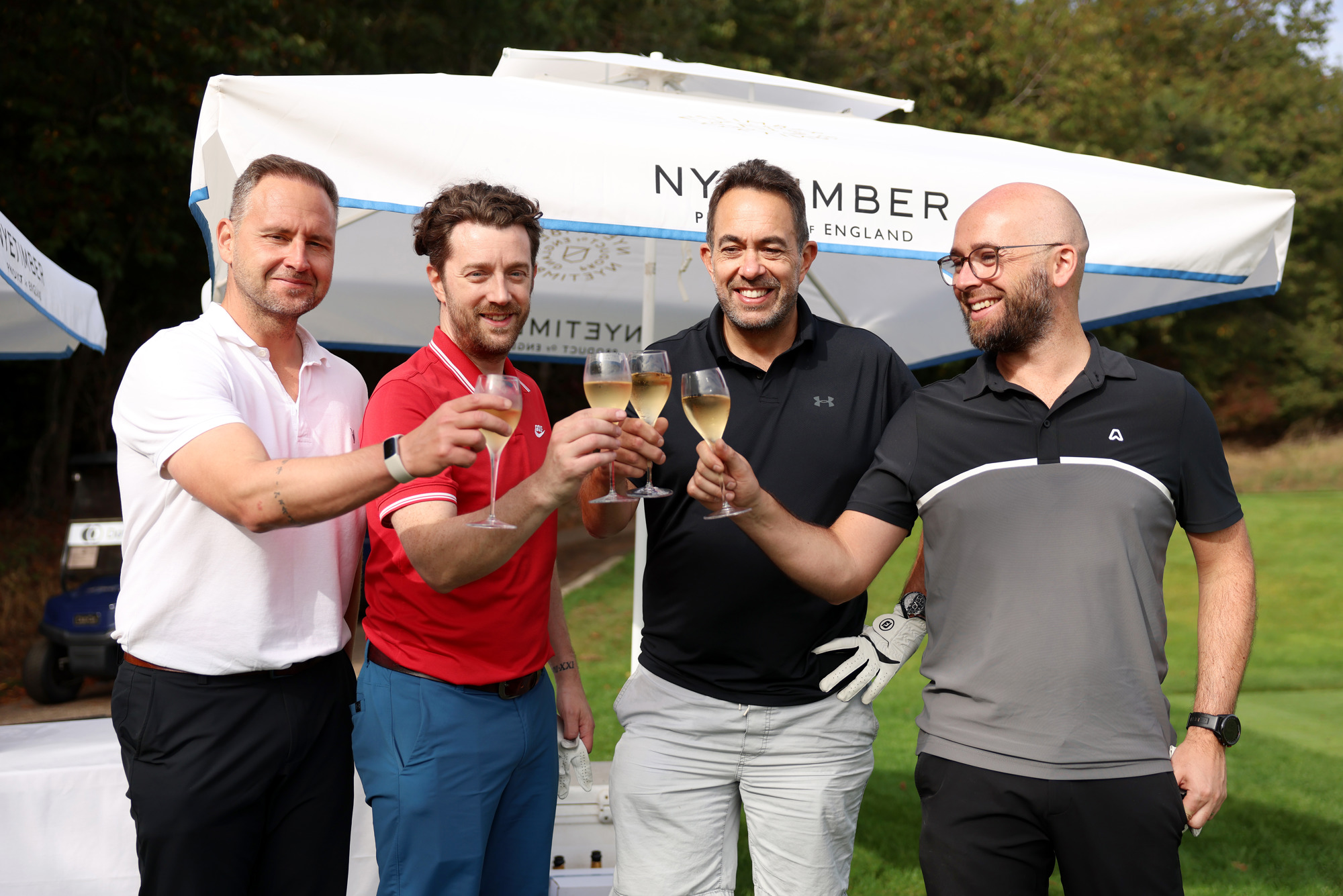 Four men clink glasses of Nyetimber